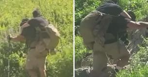 Los excursionistas miran más de cerca la mochila del hombre y se dan cuenta de que lleva a un compañero marine que resultó herido en combate Los excursionistas miran más de cerca la mochila del hombre y se dan cuenta de que lleva a un compañero marine que resultó herido en combate