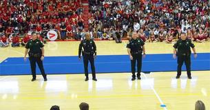 Los policías entran al gimnasio de la escuela para mostrar sus habilidades de baile Los policías entran al gimnasio de la escuela para mostrar sus habilidades de baile