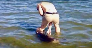 Un homme sur une plage canadienne joue avec une gentille loutre de mer qui tire sur sa jambe Un homme sur une plage canadienne joue avec une gentille loutre de mer qui tire sur sa jambe