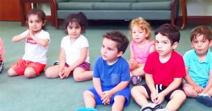 Une enseignante demande aux enfants de taper des mains, mais toute l'attention se tourne vers un garçon en t-shirt bleu Une enseignante demande aux enfants de taper des mains, mais toute l'attention se tourne vers un garçon en t-shirt bleu